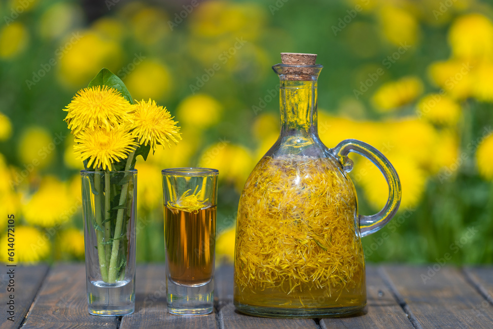 Homemade dandelion flowers tincture in glass bottle on a wooden table in a summer garden, closeup Homemade dandelion flowers tincture in glass bottle on a wooden table in a summer garden, closeup