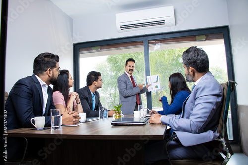 Indian businessman discussing with employees about finance and success of company as presentation, Business statistics performance concept.