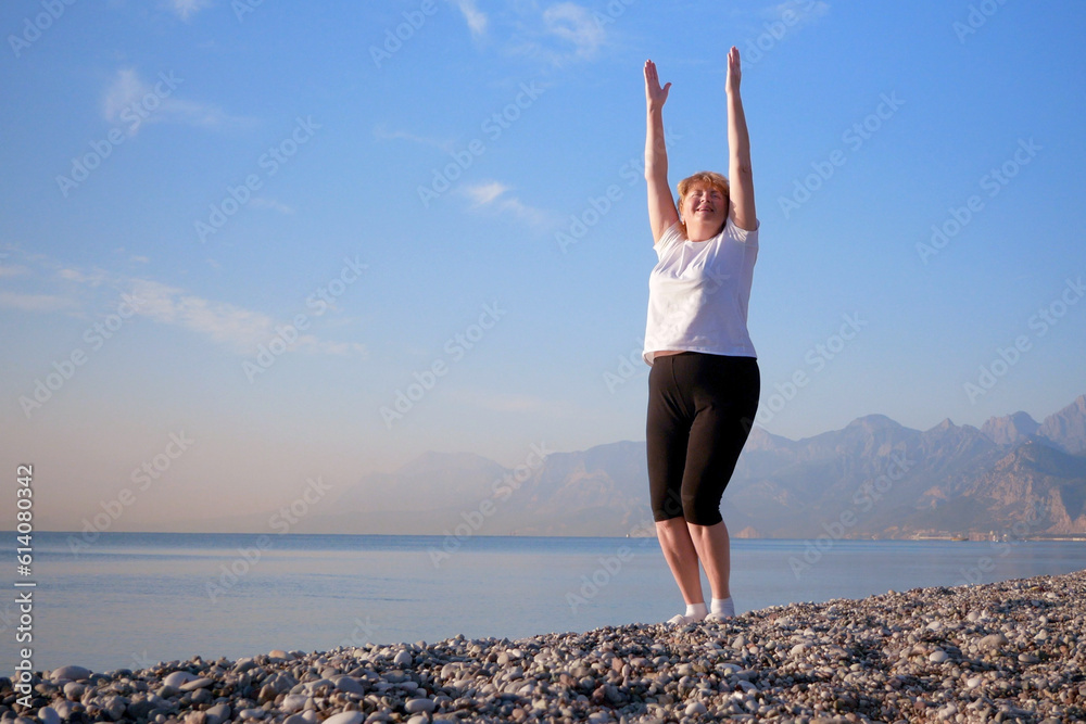 Senior woman doing yoga performing asanas and enjoying life on the beach sea, sunset time Senior woman doing yoga performing asanas and enjoying life on the beach sea, sunset time