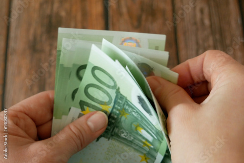 hand holding big stack of euro money on wooden background. money cash