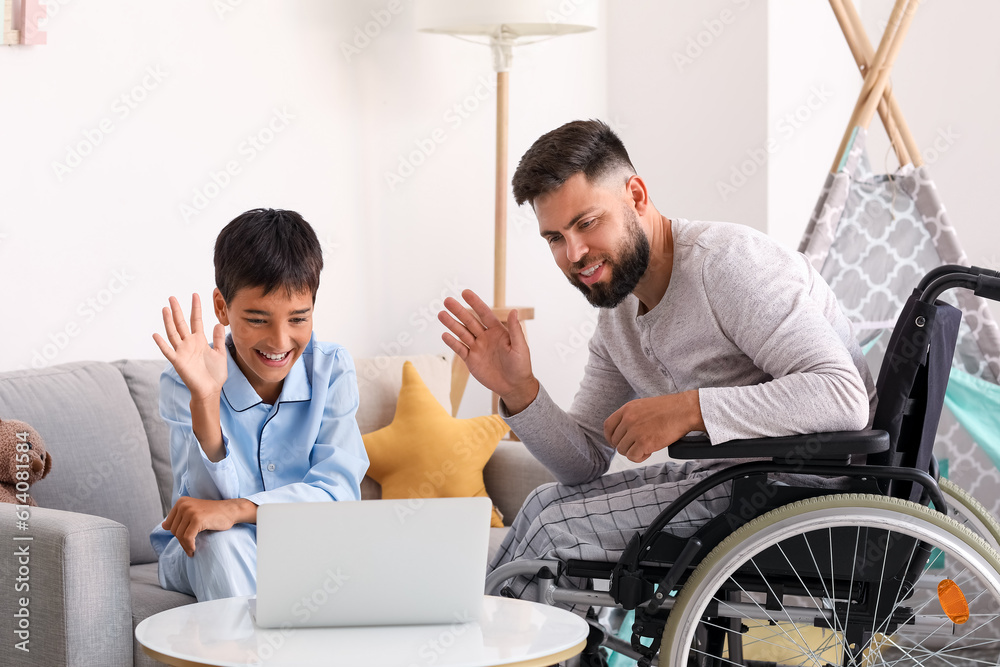 Little boy and his father in wheelchair video chatting at home Little boy and his father in wheelchair video chatting at home