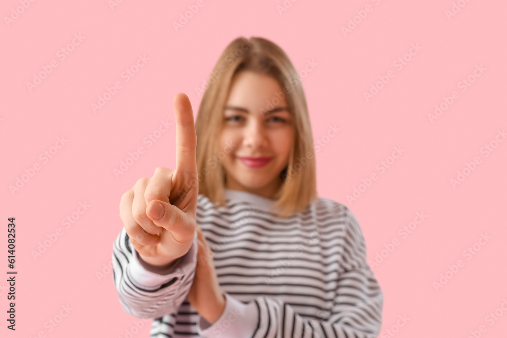 Young woman in striped sweatshirt showing one finger on pink background, closeup Young woman in striped sweatshirt showing one finger on pink background, closeup