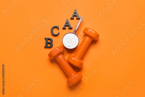 Letters BCAA, scoop with amino acid supplement and dumbbells on color background