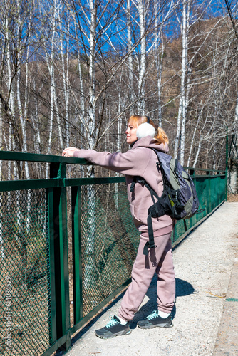 A girl in a hoodie with a backpack at the railing of the bridge.