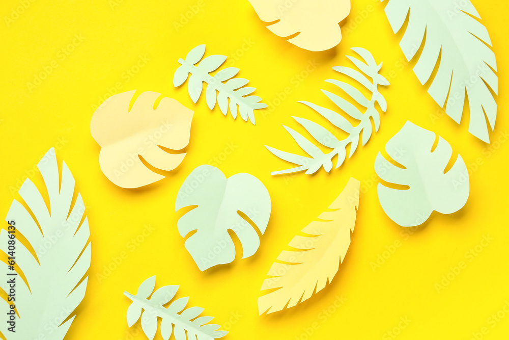 Paper tropical leaves on yellow background