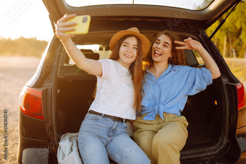 Two Young woman takes a selfie in the car during a road trip. Lifestyle, travel, tourism, nature, active life.