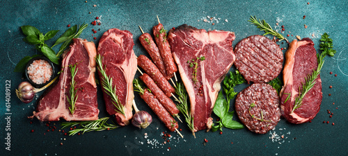 A set of steaks and veal meat. Meat products. On a black stone background. Top view.
