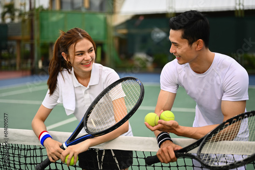 Male and female tennis players talking and resting after game over net at court. Sport activity, tennis training and competition © Prathankarnpap