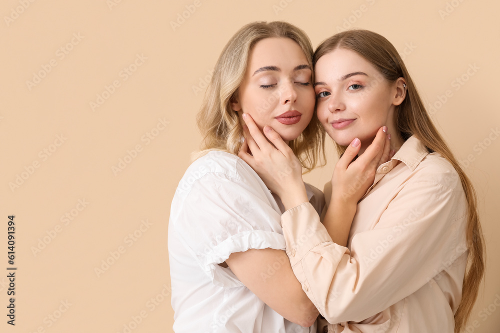Young sisters hugging on beige background Young sisters hugging on beige background