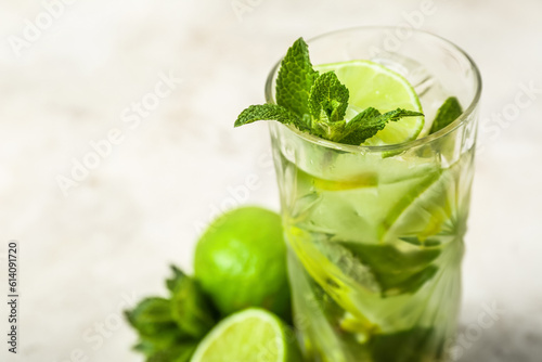 Glass of cold mojito on light background