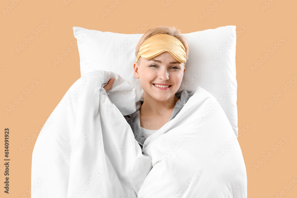 Young woman with pillow and blanket on beige background Young woman with pillow and blanket on beige background
