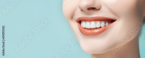 Dental care banner with a beautiful healthy smile of a young woman on light blue background with copy space.
