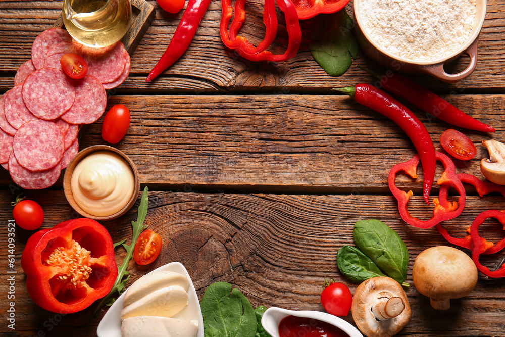 Frame made of fresh ingredients for preparing pizza on wooden background