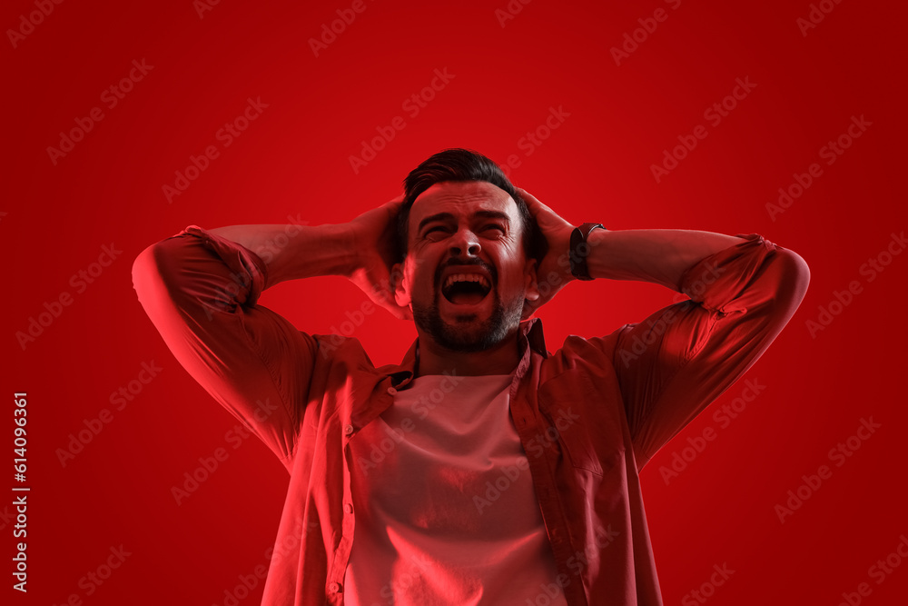 Young man having panic attack on red background Young man having panic attack on red background