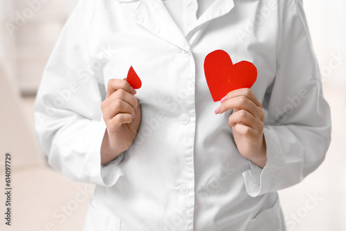 Female doctor with paper blood drop and heart in clinic, closeup