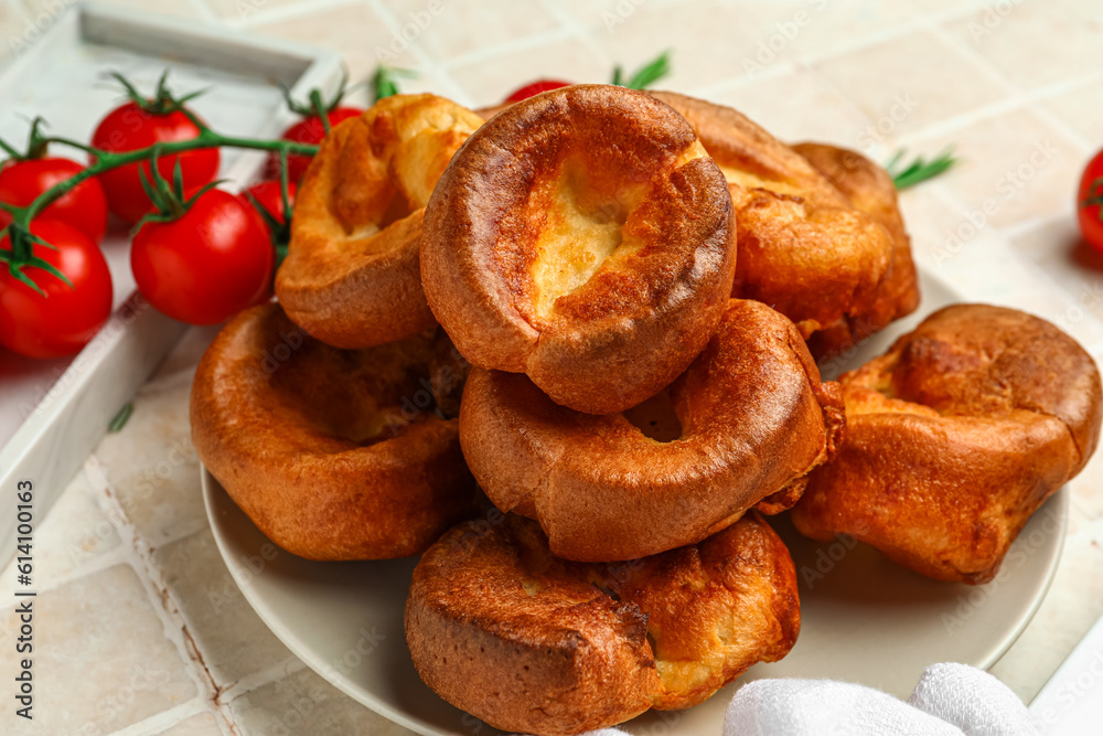 Plate with tasty Yorkshire pudding on light tile background Plate with tasty Yorkshire pudding on light tile background