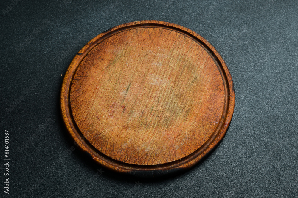 Kitchen round cutting board. Brown board. Kitchen utensils. On a dark background. Kitchen round cutting board. Brown board. Kitchen utensils. On a dark background.