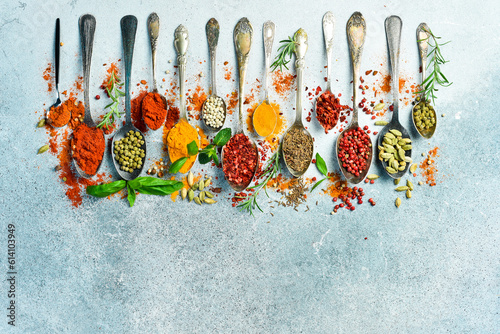 Fototapeta Naklejka Na Ścianę i Meble -  Spices and herbs in spoons on a gray stone background. Top view. Free space for text.