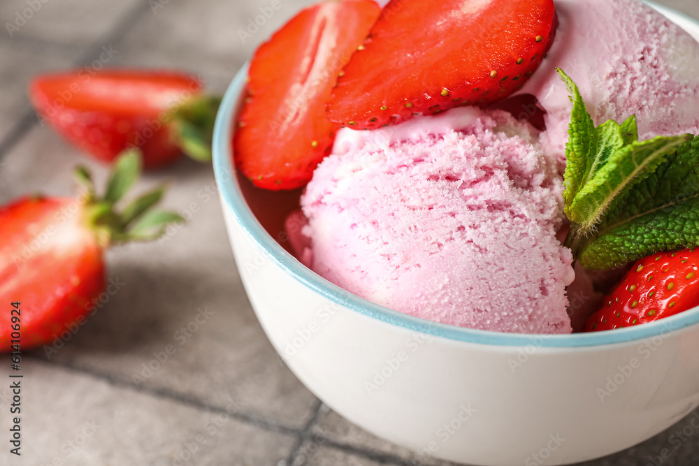 Bowl of delicious ice cream with fresh strawberries and mint on grey grunge table, closeup