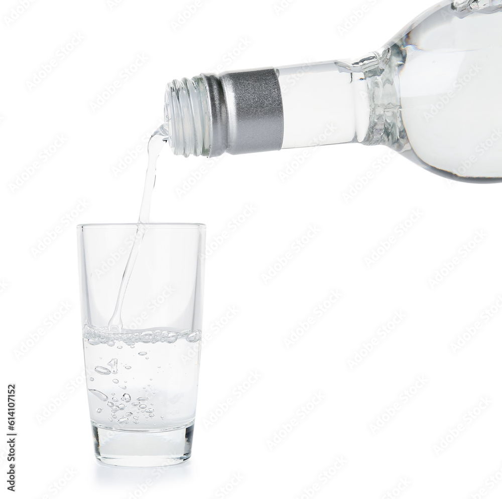 Pouring of vodka from bottle into glass on white background