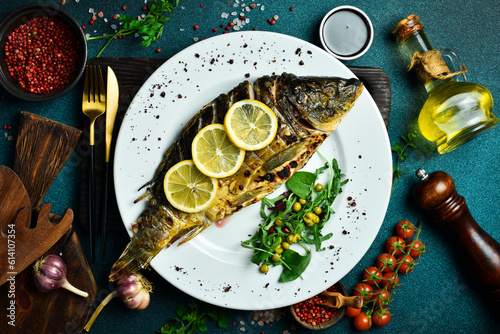Baked carp fish with lemon and herbs. Barbecue menu. Free space for text. Close up.