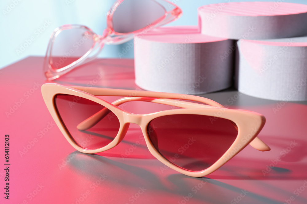 Podiums with different stylish sunglasses on colorful background Podiums with different stylish sunglasses on colorful background