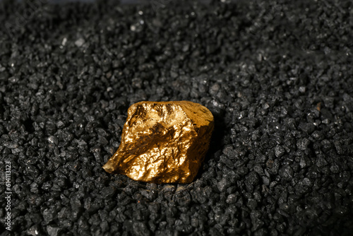 Golden nugget on black coal, closeup