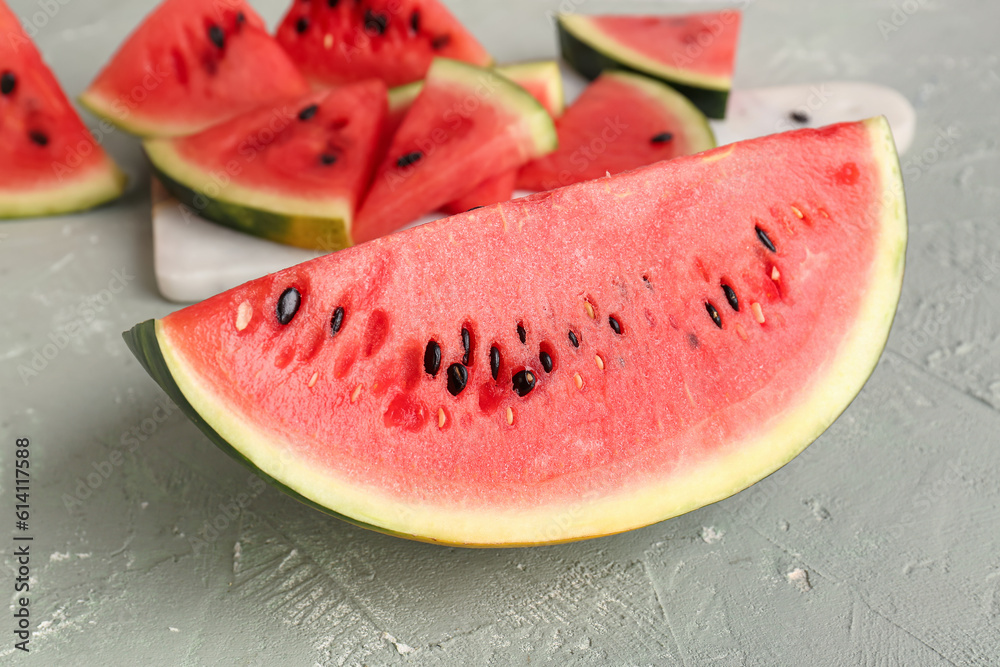 Board with pieces of fresh watermelon on grey table