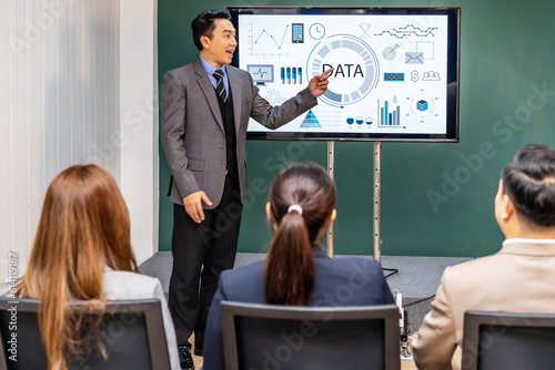 Asian Male Chief Analyst Holds Meeting Presentation for a Team of Economists at boardroom meeting. He Shows Digital Interactive Whiteboard with Growth Analysis, Charts, Statistics and Data