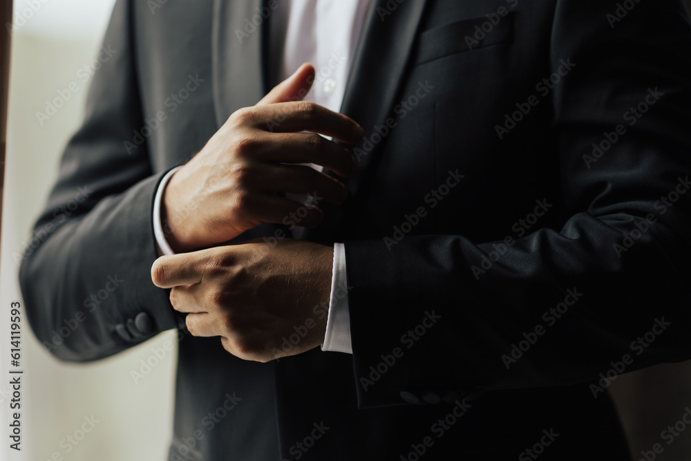 Grooms morning preparation. Cropped photo of elegant young fashion man dressing up for wedding celebration. Groom dressed in modern black formal suit and white shirt, he getting ready for event.