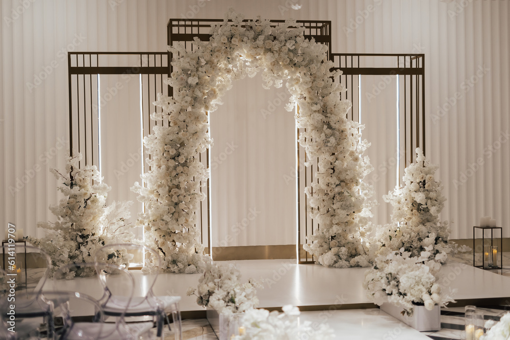 Wedding arch decorated with white flowers in the luxury restaurant. Beautiful wedding set up in the luxury locale.