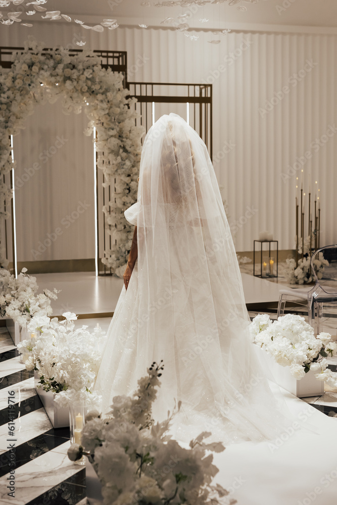 A bride in a white wedding long dress
goes to luxury elegant wedding decoration.