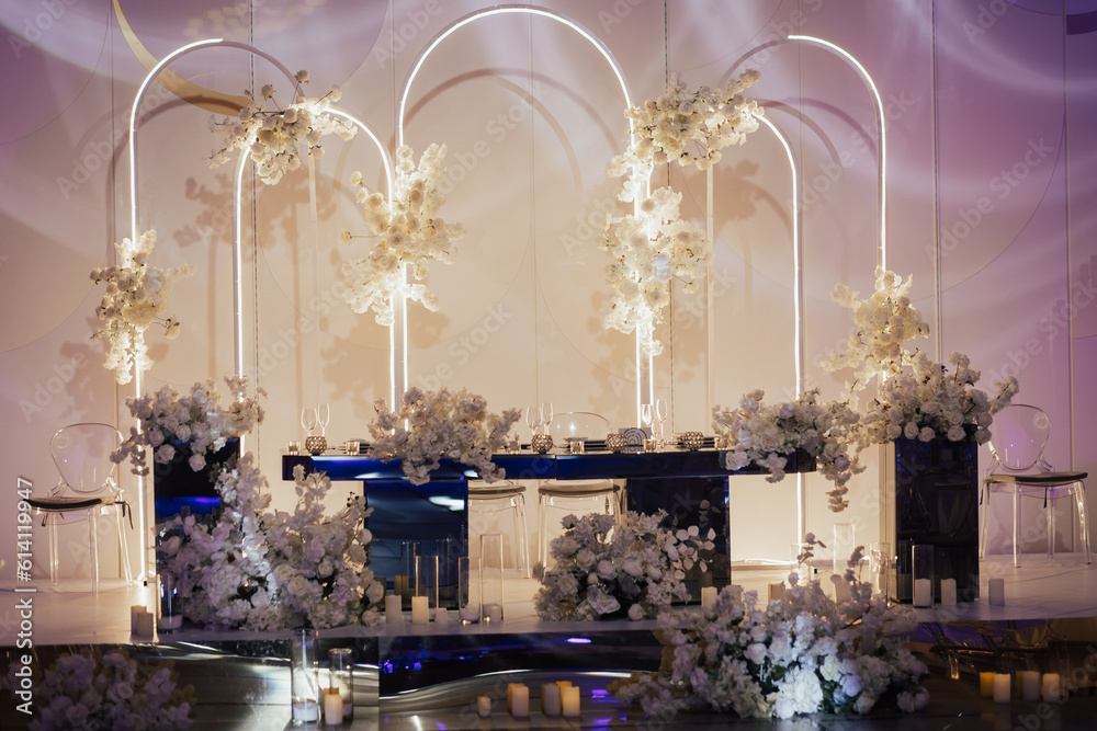 Luxury elegant classic table for the bride and groom decorated with white flowers and vases with candles.
