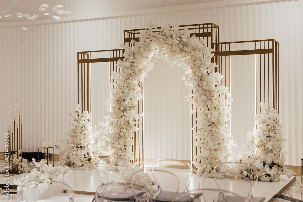 Wedding arch decorated with white flowers in the luxury restaurant. Beautiful wedding set up in the luxury locale.