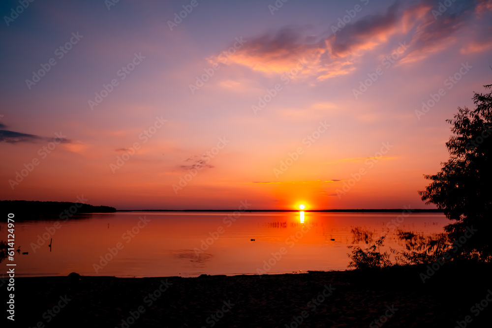 Beautiful sunset above the lake with blue sky and rare fluffy pink clouds. Sun path. Seascape. Calm water. Natural background. Nature landscape. Summertime travelling. Warm evening concept. No people Beautiful sunset above the lake with blue sky and rare fluffy pink clouds. Sun path. Seascape. Calm water. Natural background. Nature landscape. Summertime travelling. Warm evening concept. No people