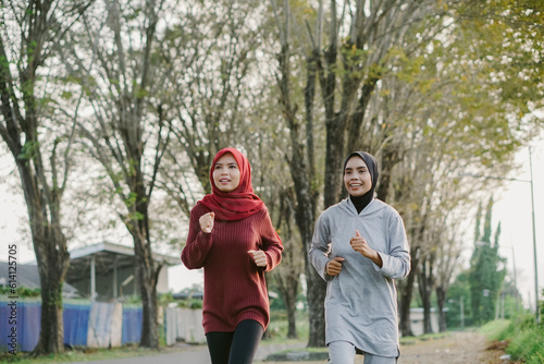 two asian muslim women running and exercising outdoors