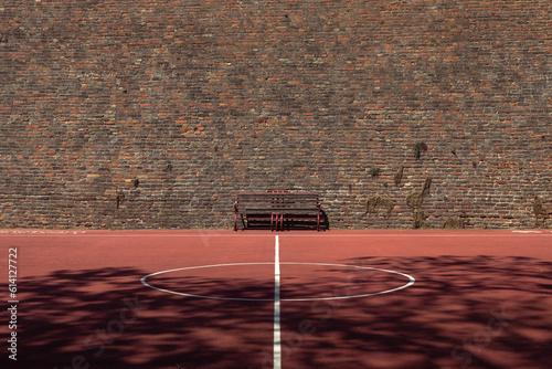 Basketball playground in front of the high-rise brick wall.