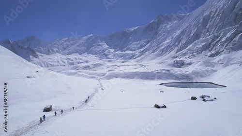 Aerial panning view group of trekkers on famous Tilicho lake trek with tiny alpine lake background. Nepal popular treks. Himalayas tours and mountains trekking concept photo