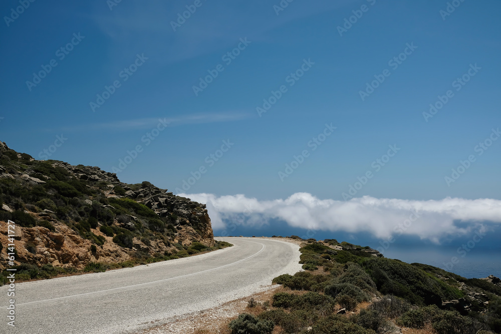 A lonely road on a hill and clouds on the same level in Ios cyclades Greece