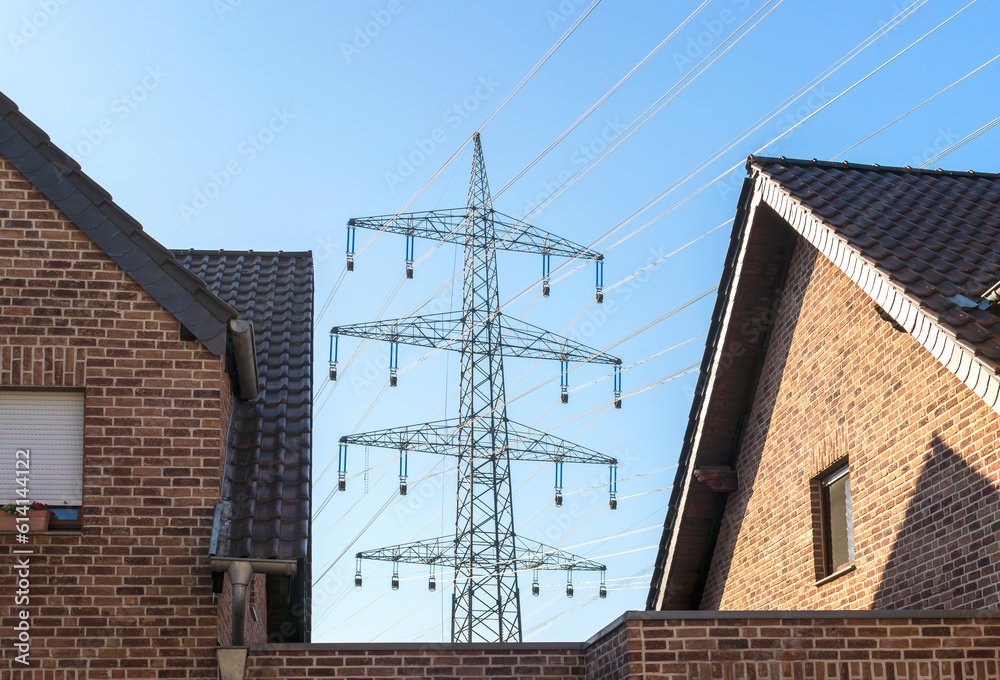 Fotografie High voltage power pylon between houses