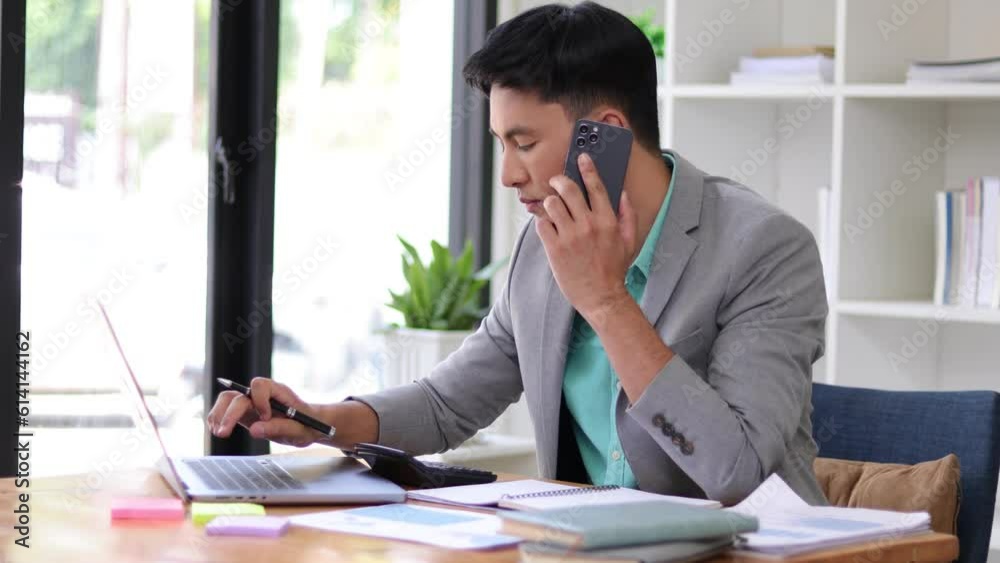 Serious businessman working on documents on laptop while talking with someone on the phone. Serious businessman working on documents on laptop while talking with someone on the phone.