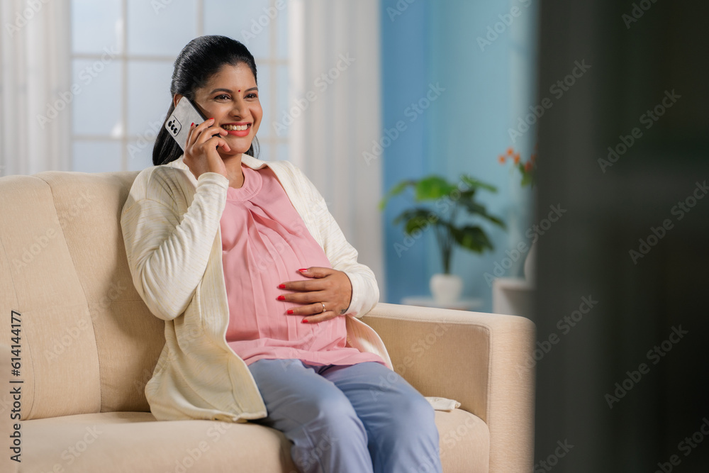 Happy indian pregnant woman talking on mobile phone by touching or feeling the tummy - concept of communication, Expectation and positive emotion Happy indian pregnant woman talking on mobile phone by touching or feeling the tummy - concept of communication, Expectation and positive emotion