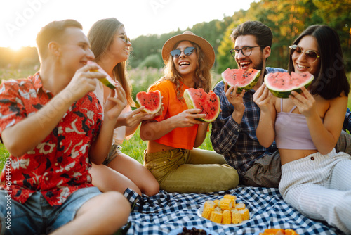 Young people eating watermelon on the picnic outdoors. People, lifestyle, travel, nature and vacations concept.