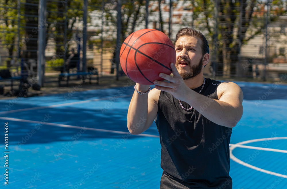 Athletic lebanese man in sportswear playing basketball game, successfully throws ball into the basket ring. Young guy on urban city summer court. Fitness routine on sports field. Motivation. Outdoors