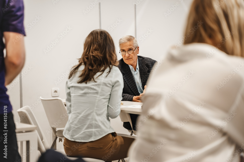 Obraz premium Older businessman talking to his brunette female employee