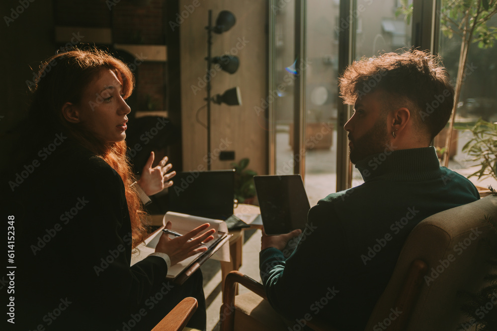 Ginger female person explaining something to her male colleague while gesticulating with her hands Ginger female person explaining something to her male colleague while gesticulating with her hands