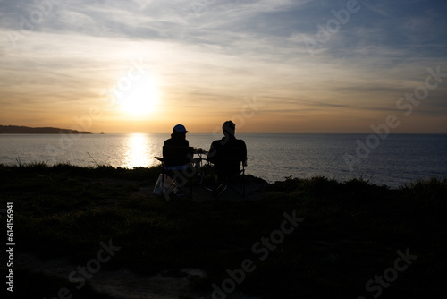 silhouette of a couple sitting on a pier see the sunset
