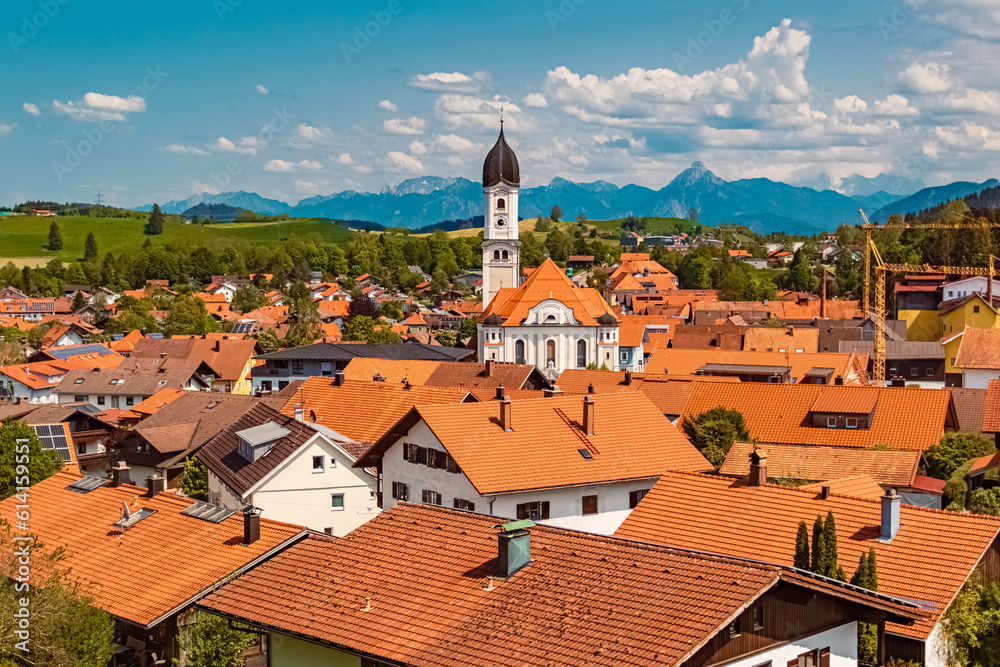 Alpine summer view with a church and the alps in the background at Nesselwang, Ostallgaeu, Bavaria, Germany