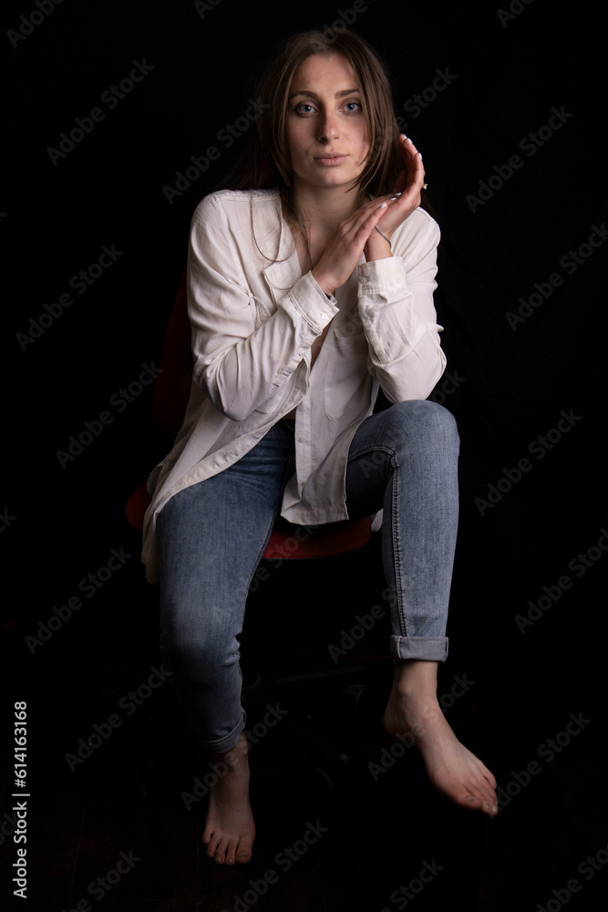Beautiful young girl in a white shirt and jeans on a black background Beautiful young girl in a white shirt and jeans on a black background