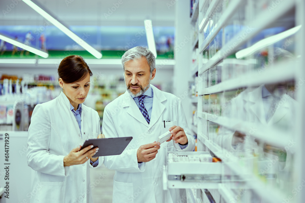 A female and male pharmacist looking at the tablet while doing inventory.